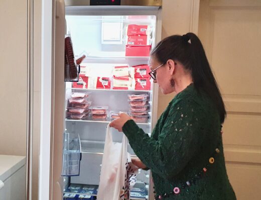 Diakoniatyöntekijä kerää avustuskassiin elintarvikkeita jääkaapista.