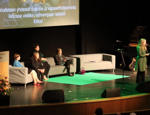 Diakoniabarometrin tutkijat istuvat sohvalla, Titi Gävert puhuu Kulttuuritalon lavalla.
