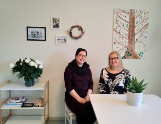 Kotoa kotiin -hankkeen projektipäälliköt Anna-Leena Atkinson ja Maija Eerola istuvat pöydän ääressä.