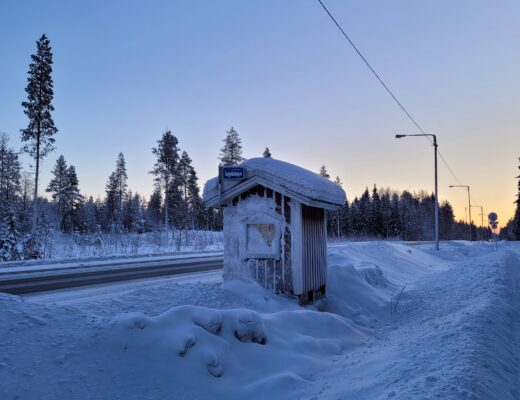 Bussipysäkki lumihangessa maaseudun tiellä.