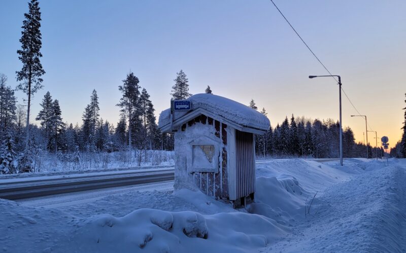 Bussipysäkki lumihangessa maaseudun tiellä.